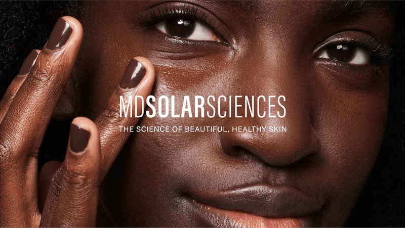 Model applying MD Solar Sciences products to face with MD Solar Sciences logo on top of the image. Text written under the logo reads: 
